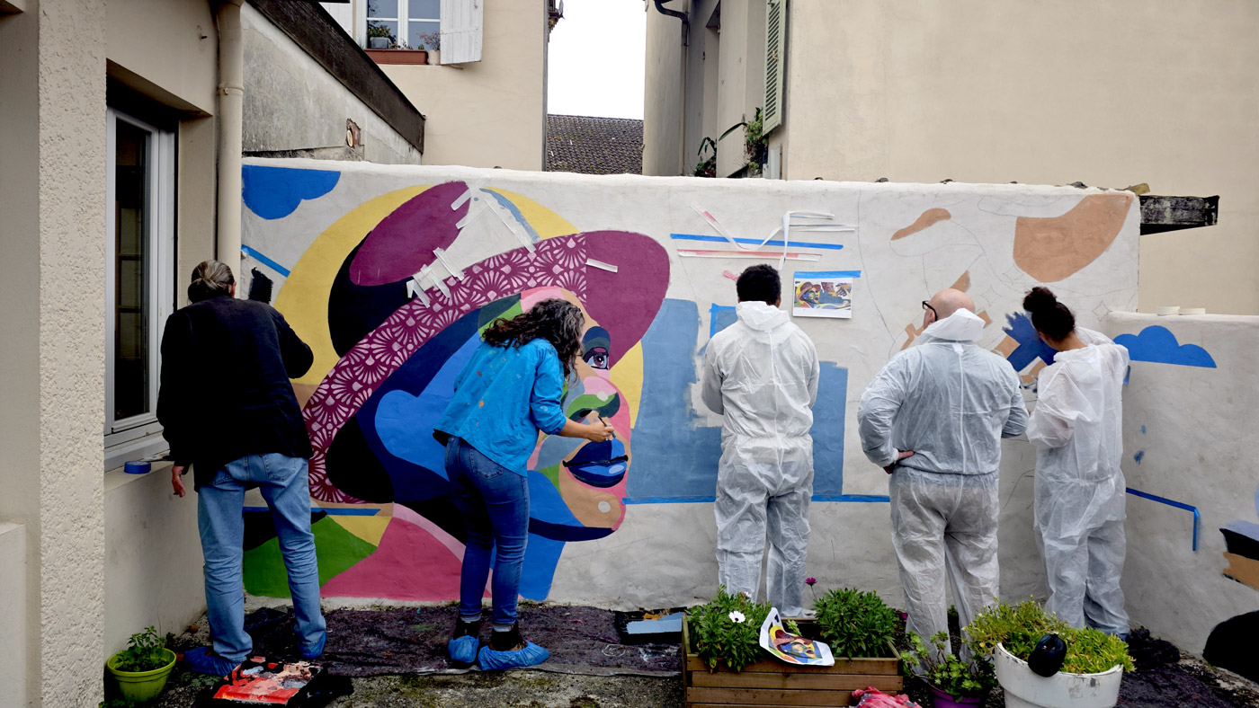 Une fresque murale collective, les participants peignant la fresque avec pochoirs et bombes aérosols